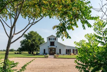 Elegant and rustic white barn venue with stained wood accents nestled in trees