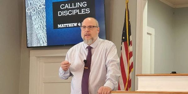 A man giving a sermon titled 'Calling Disciples' in a church setting.