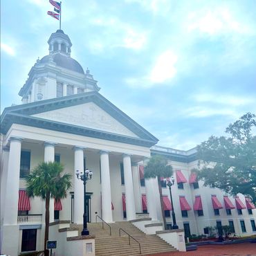 Florida Capitol government building with large columns and red-striped window awnings.