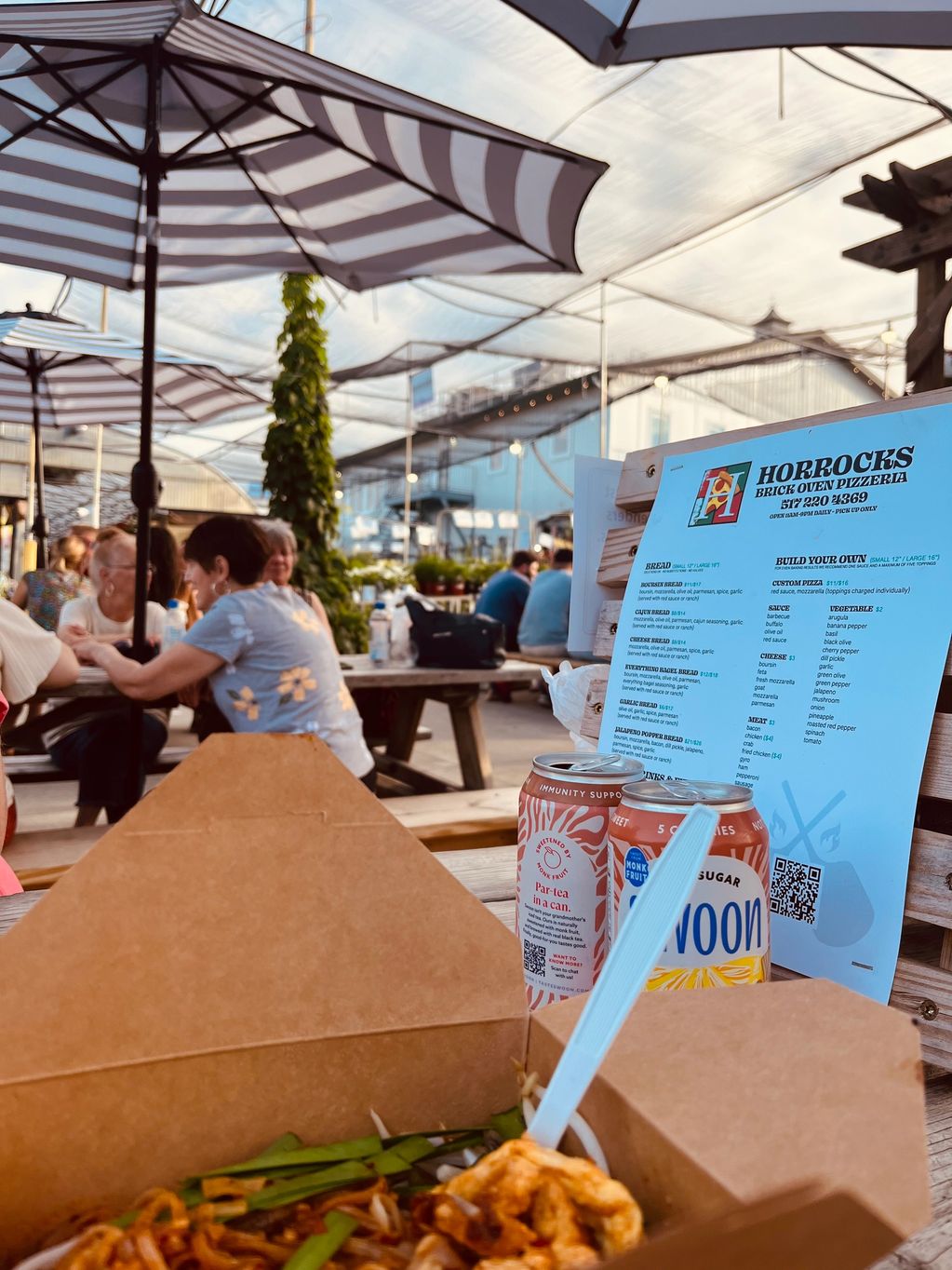 people eating, striped umbrellas at picnic tables