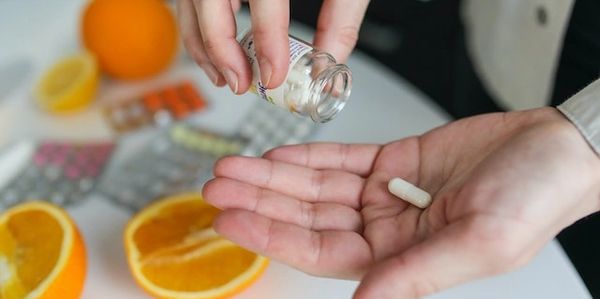 <img src="taking-medication-with-oranges.jpg" alt="Taking pill with oranges and meds on table">