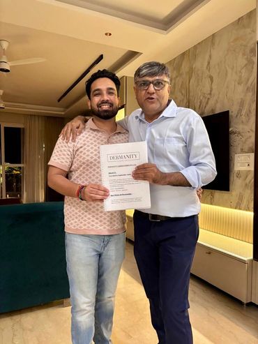Two men happily holding a document labeled DERMANITY indoors.