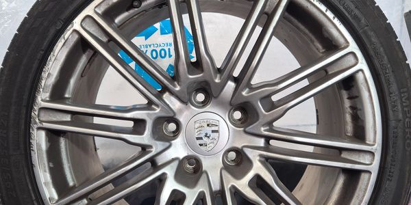 Close-up of a Porsche alloy wheel with tire and recycling label.