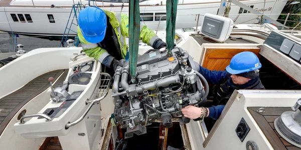 Two workers installing an engine on a boat.
