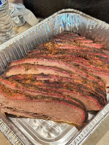 Sliced smoked brisket in a foil tray.