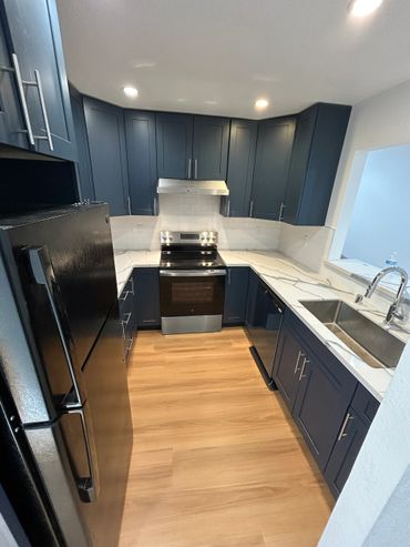Modern kitchen with dark blue cabinets and marble countertops.