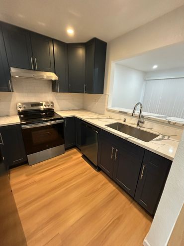 Modern kitchen with dark cabinets, marble countertops, and stainless steel appliances.
