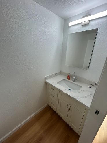 Minimalist bathroom vanity with white countertop and mirror.