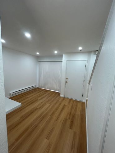 Empty room with wood flooring and white walls.