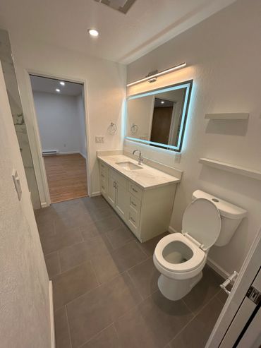 Modern bathroom with illuminated mirror and sleek design.