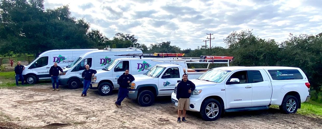 Experienced plumbers stand proudly with branded trucks, symbolizing reliability. Plumbing services.