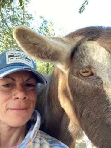 Woman taking a close-up selfie with a brown donkey outdoors.