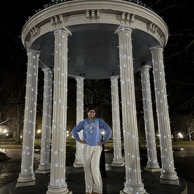 Person standing under a gazebo with illuminated columns at night.