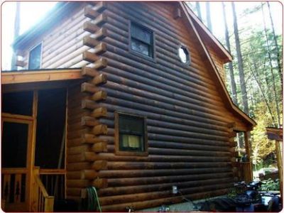 A rustic log cabin with burn damage across the side of the home