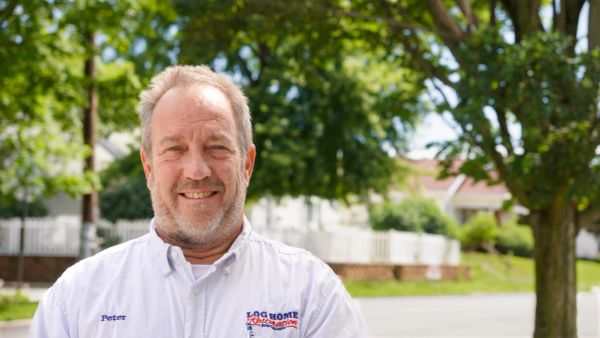 Smiling man named Peter in a Log Home Restoration shirt outdoors.