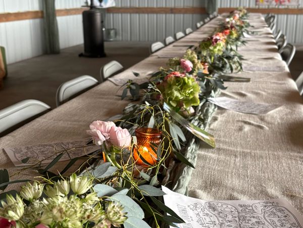 Row of tables with floral garland and candles along the center.