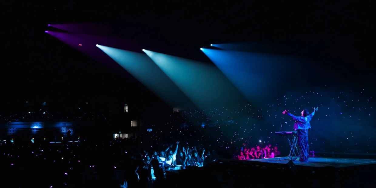 Musician performing on stage with vibrant blue and purple lights.