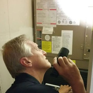 Inspector inspecting a furnace and a/c unit