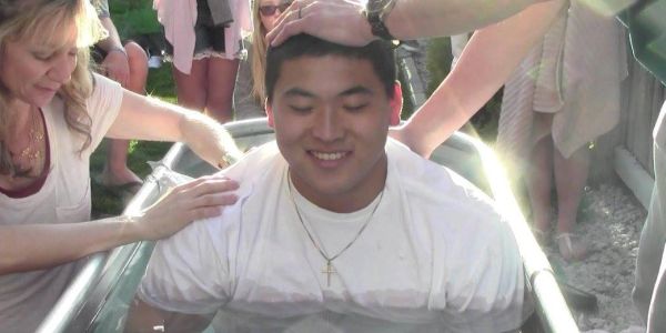 Young man smiling while supported by people in a tub.