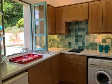 Pool kitchen showing fridge, stove and washing machine, overlooking the pool.