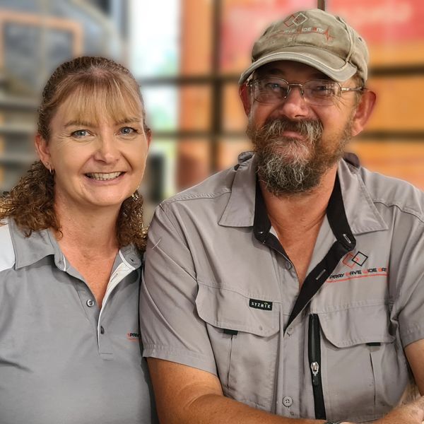 Smiling couple wearing matching gray work uniforms, sitting closely together.