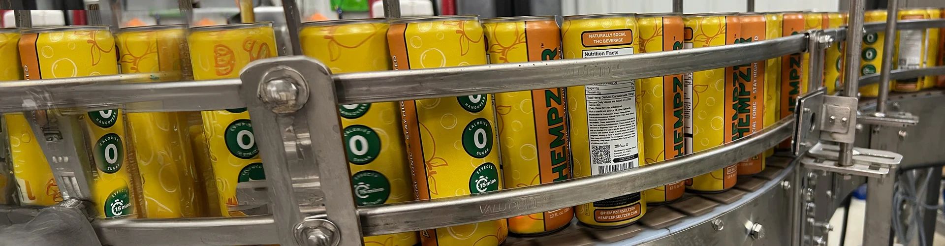 Yellow Hempz beverage cans on a metal production line conveyor.