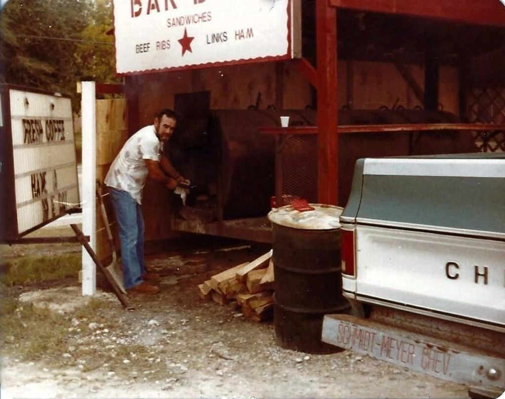 A picture of my dad tending the fire in a bbq pit