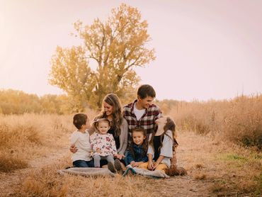 A happy family sitting together outdoors in autumn golden hour.