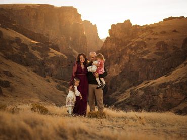 Family of four smiling together in a golden mountainous landscape.
