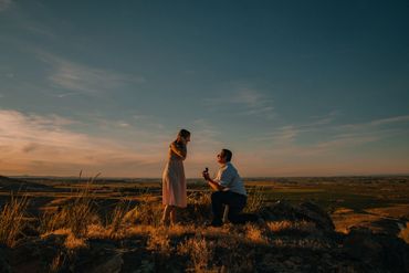 Man proposing to woman on a hill during sunset.