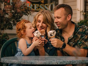 Family enjoying ice cream cones together at an outdoor cafe.