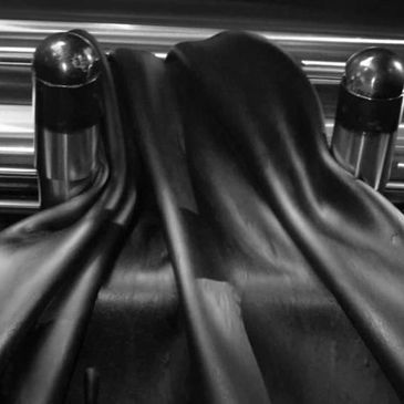 Black latex or rubber material draped over cylindrical shapes.