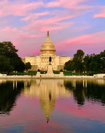 The Capitol building reflected in water during sunset.