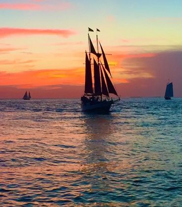 Sailboat silhouetted against a vibrant sunset on the water.