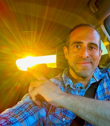 Man pointing at the sun shining through a car window.