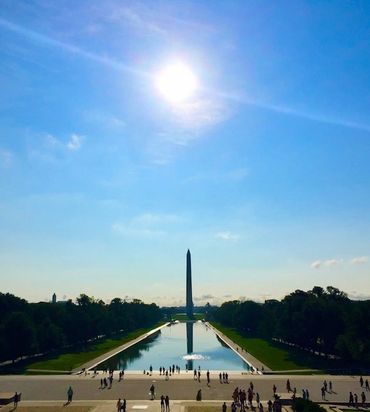 The Washington Monument with its reflection in the water under a bright sun.