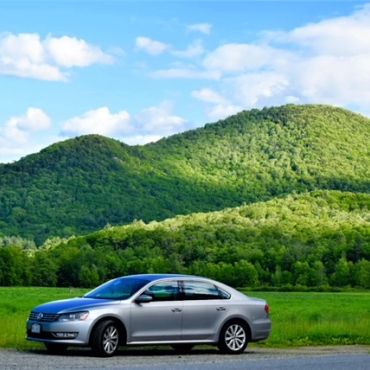Silver car parked by a scenic mountain landscape.