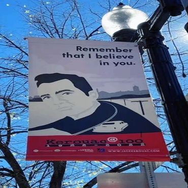 Banner with quote and portrait of Jack Kerouac on a street lamp.