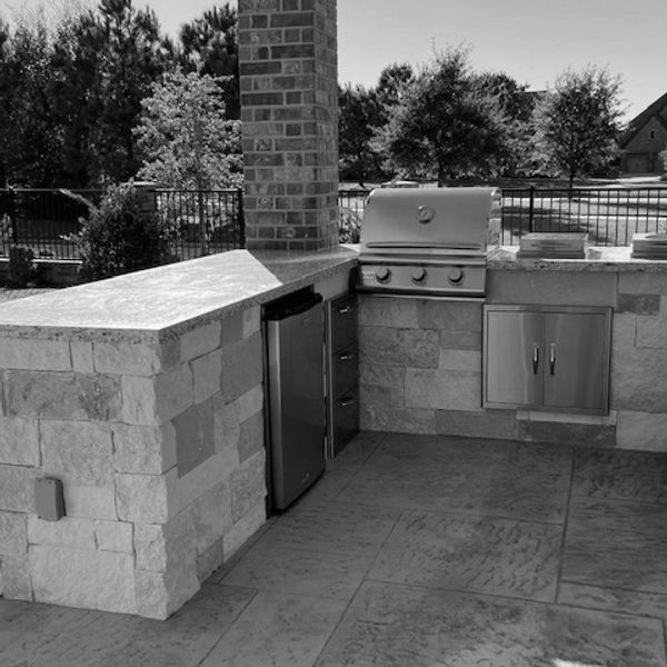 Outdoor kitchen with grill and storage under a chimney.