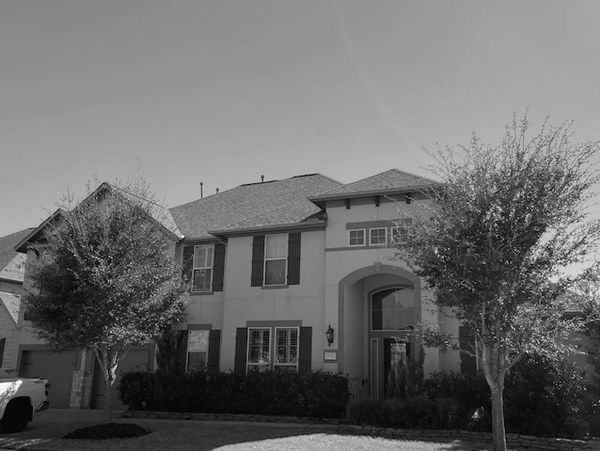 Two-story suburban house with trees in front.