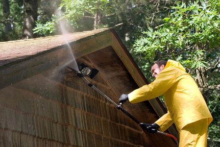 Man Pressure Washing Under Exterior Wood Eaves