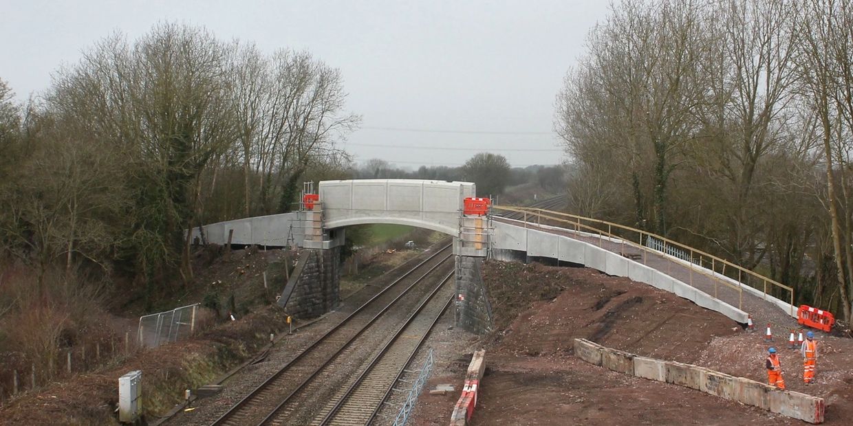 Newly constructed pedestrian bridge over railway tracks in a rural area.