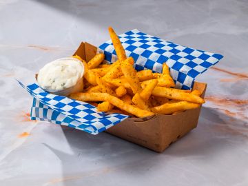 Seasoned fries with dip in a cardboard tray.
