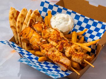 Grilled chicken skewers with fries and pita bread.