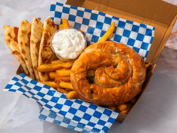 Greek meal with spanakopita, pita bread, fries, and tzatziki sauce.
