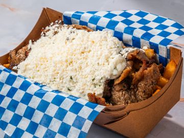 Box of food with meat, fries, and cheese topping.