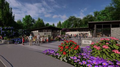 A lively outdoor scene with people gathering near modern buildings surrounded by colorful flowers.