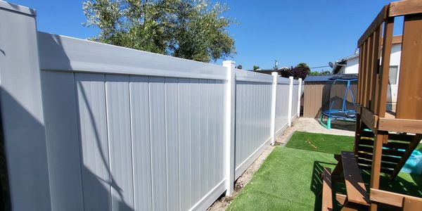 White vinyl fence along backyard with play area.