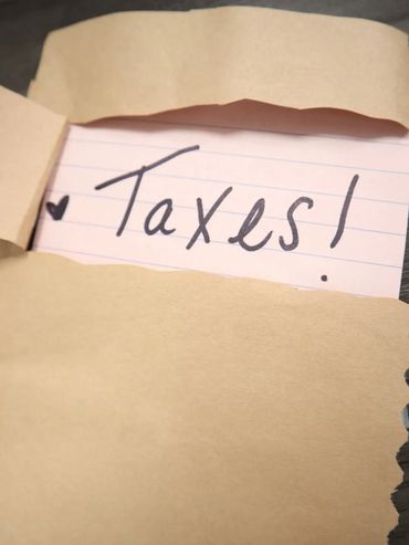 A note with the word 'Taxes!' partially visible inside a torn envelope.
