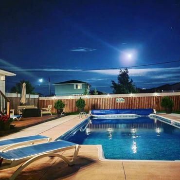 Night sky and moon overlooking backyard inground pool